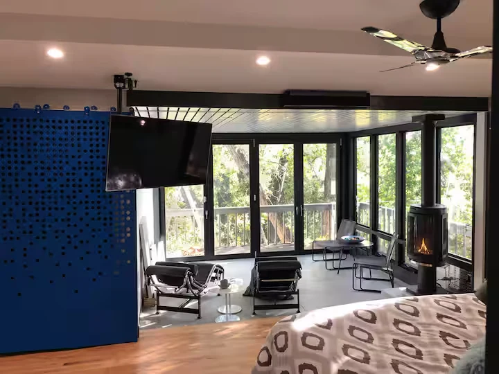 Bedroom opening onto a glass-enclosed sitting lounge with fireplace and blue privacy screen