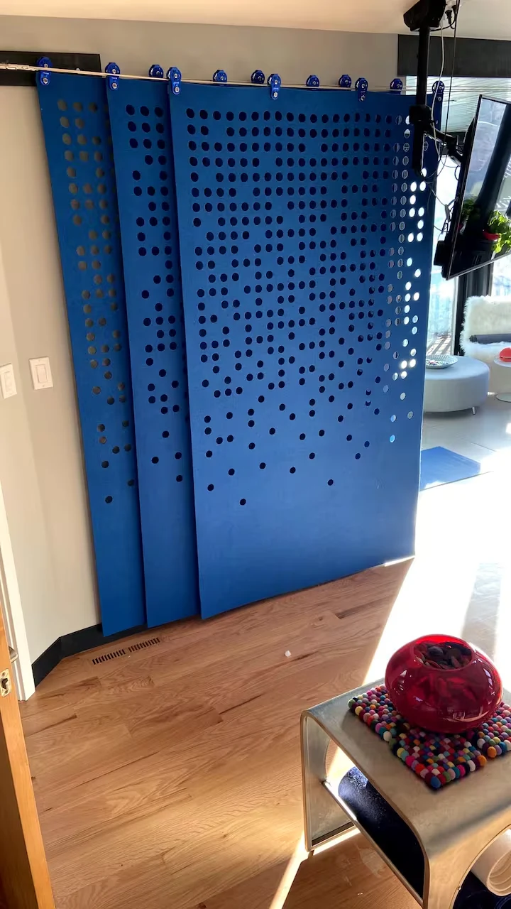 Blue perforated sliding privacy screens suspended from overhead cable guides