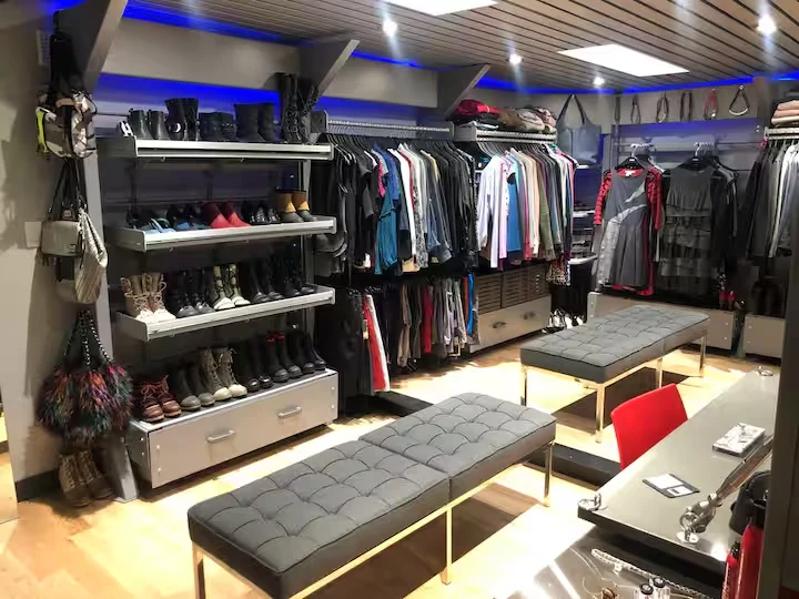 Walk-in closet with hanging clothes, shoe shelves and two upholstered benches