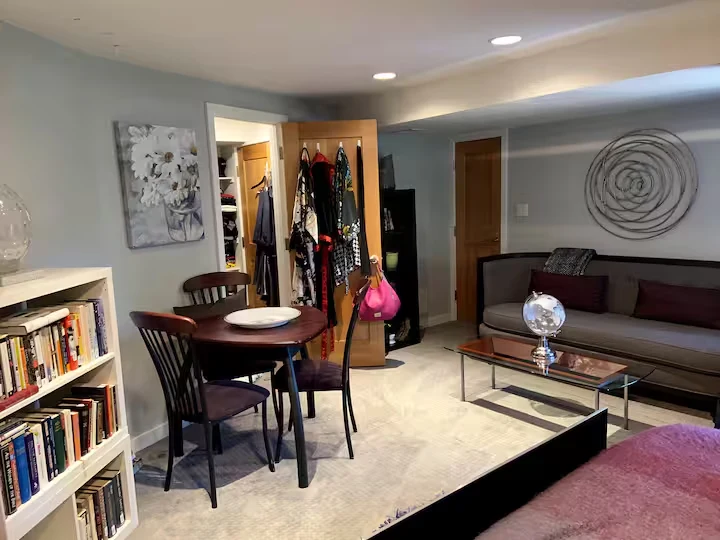 Suite sitting area with sofa, glass coffee table, round work table, chairs and bookshelves