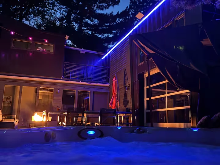 Nighttime view from the hot tub toward the courtyard and blue-lit industrial residence