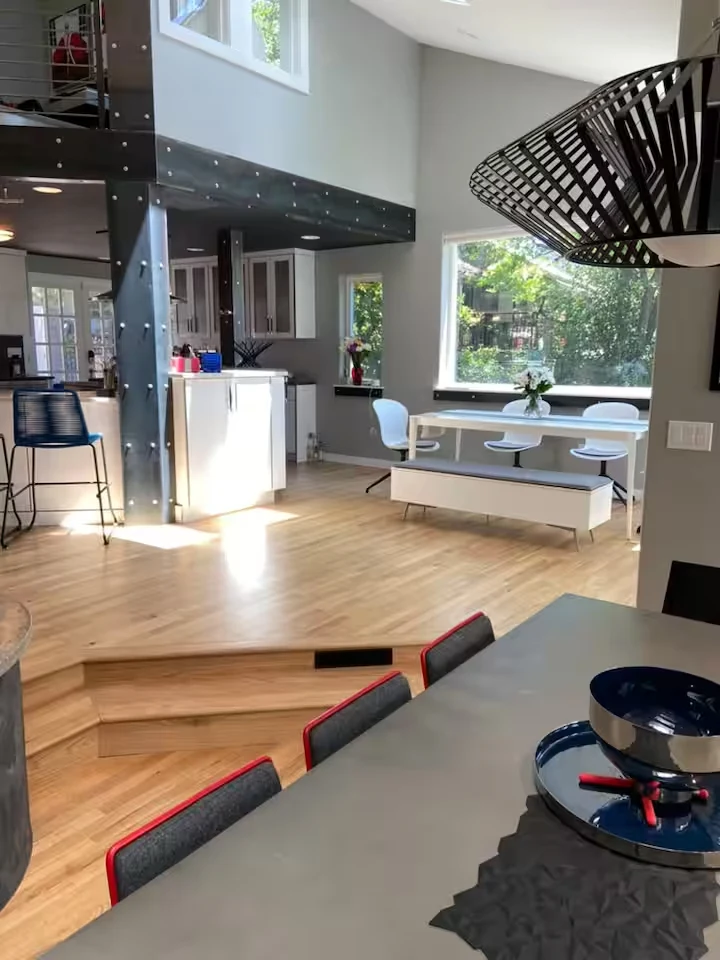 Open dining area with steel loft beams, sculptural pendant light, hardwood floors and breakfast nook