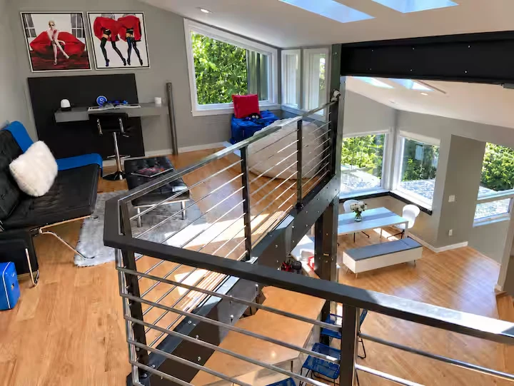 Upper-level seating and workspace overlooking the dining nook through steel-and-cable stair railings