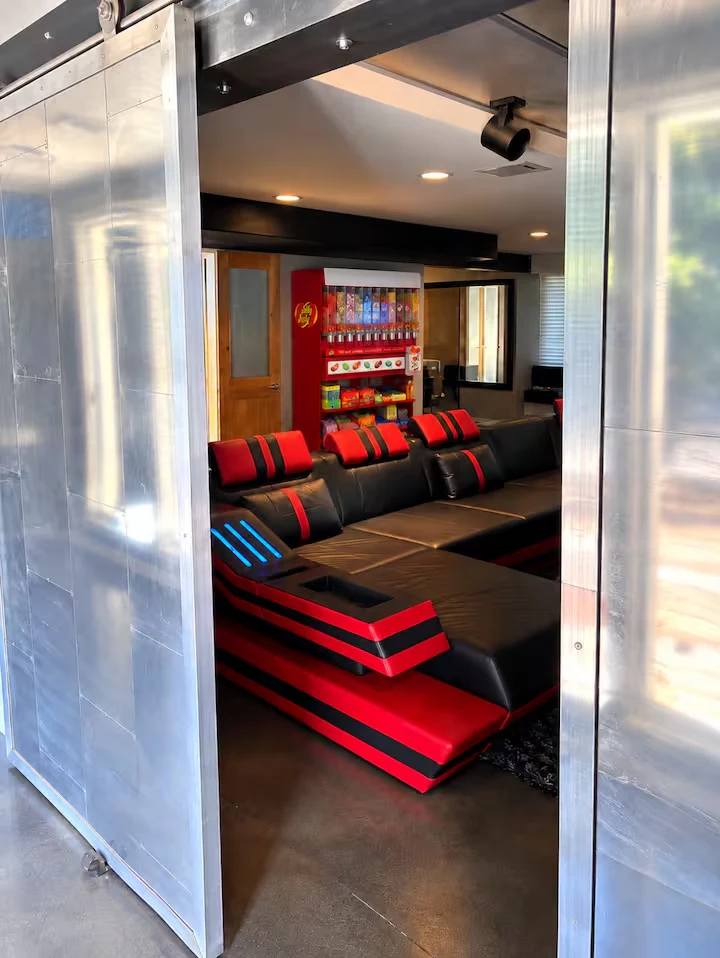 Metal sliding doors opening onto a red-and-black cinema sectional and candy dispenser
