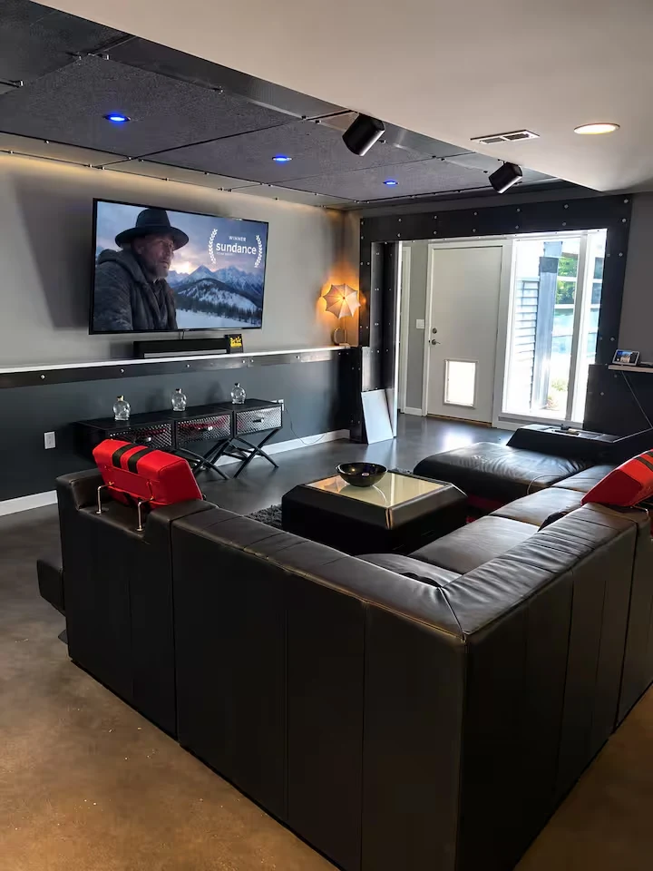 Cinema sectional and screen beneath blue ceiling lights beside an exterior door